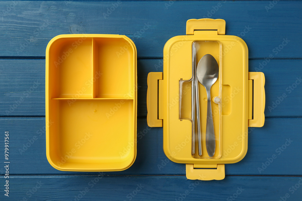 Yellow lunch box with cutlery on blue wooden table, top view Yellow lunch box with cutlery on blue wooden table, top view