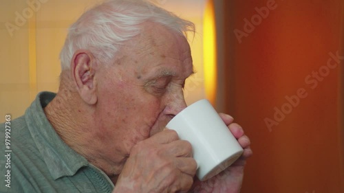 Elderly man enjoying a warm beverage while seated at home during the afternoon