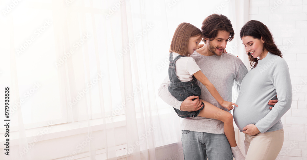 Expecting New Baby. Pretty Little Girl Tenderly Touching Mother's Pregnant Belly While Bonding With Parents Near Window At Home Expecting New Baby. Pretty Little Girl Tenderly Touching Mother's Pregnant Belly While Bonding With Parents Near Window At Home