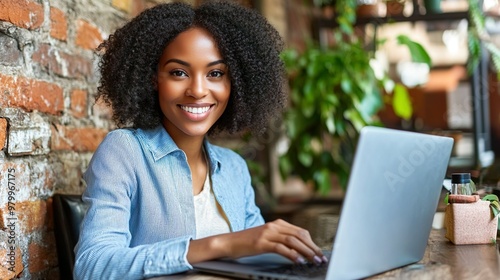 African American Woman Using Laptop Smiling In Cozy Cafe Ambiance Working Remotely