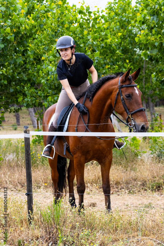 Young woman mounting horse in countryside training area Young woman mounting horse in countryside training area