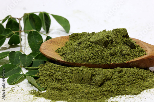 Moringa leaves (Moringa Oleifera) and moringa powder in wooden spoon isolated on white background. photo