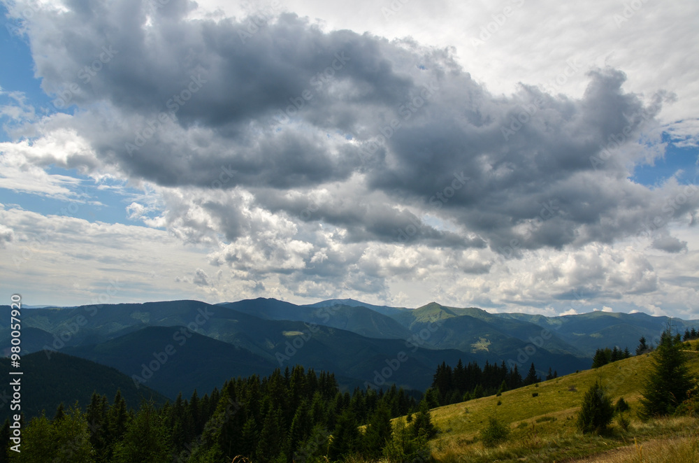 Foreground features green trees and rolling hills covered in dense forests with multiple layers of mountain ridges in the background. Breathtaking view of a mountainous region of Ukrainian Carpathians Foreground features green trees and rolling hills covered in dense forests with multiple layers of mountain ridges in the background. Breathtaking view of a mountainous region of Ukrainian Carpathians