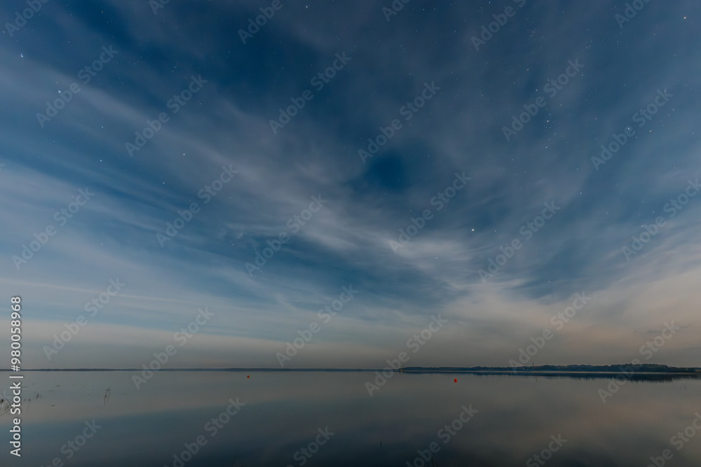 A tranquil lake at dusk, with small boats lined along the shore. The smooth water reflects the evening sky, filled with soft clouds and a few stars. The calm atmosphere creates a peaceful A tranquil lake at dusk, with small boats lined along the shore. The smooth water reflects the evening sky, filled with soft clouds and a few stars. The calm atmosphere creates a peaceful