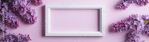 A beautiful white frame surrounded by lilac flowers on a soft pink background, perfect for photo display or artistic projects.