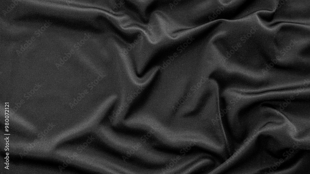 Obraz premium A detailed close-up of black fabric with natural creases and folds, capturing its smooth texture and subtle sheen. Ideal for fashion, fabric patterns, or background designs
