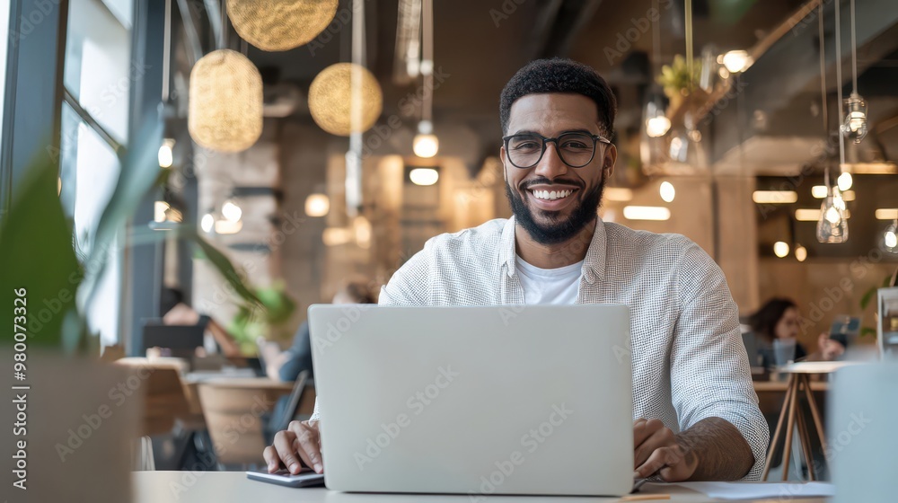 Smiling entrepreneur working on a laptop in a co-working space Smiling entrepreneur working on a laptop in a co-working space