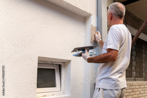 Construction worker applying final decorative facade plaster paste. Home renovation. Builders apartment improvement or restoration works.