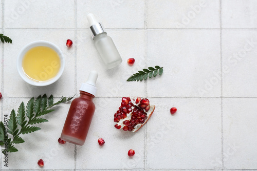 Photos Composition with bottles of essential oil, honey, pomegranate and fern leaves on