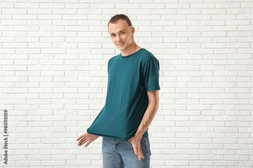 Handsome young man in stylish t-shirt near white brick wall Handsome young man in stylish t-shirt near white brick wall