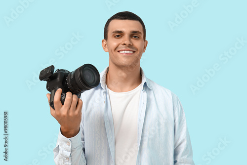 Portrait of male photographer with modern camera on blue background