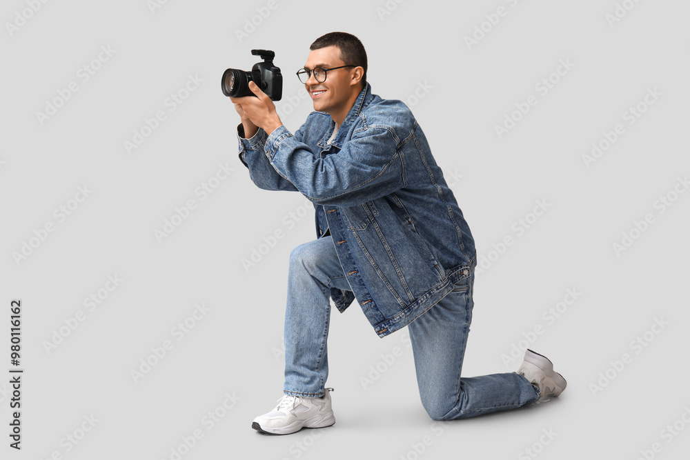 Male photographer with modern camera on grey background Male photographer with modern camera on grey background