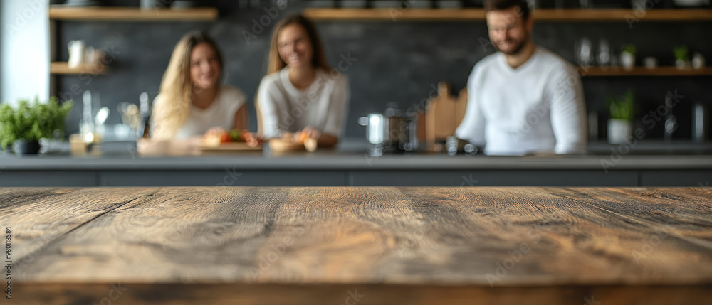 A warm kitchen scene with wooden table in foreground and happy family blurred in background. A warm kitchen scene with wooden table in foreground and happy family blurred in background.