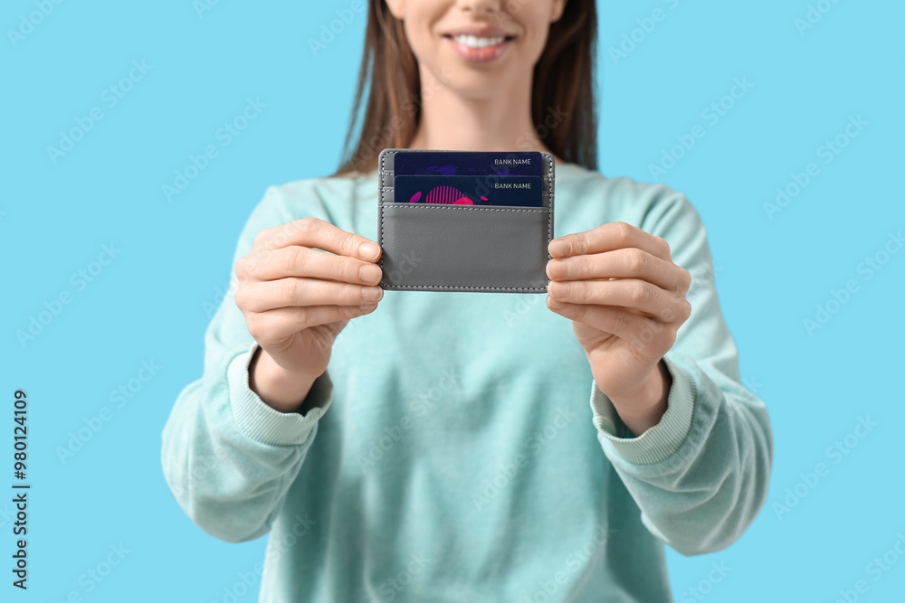 Woman with credit card holder on blue background Woman with credit card holder on blue background