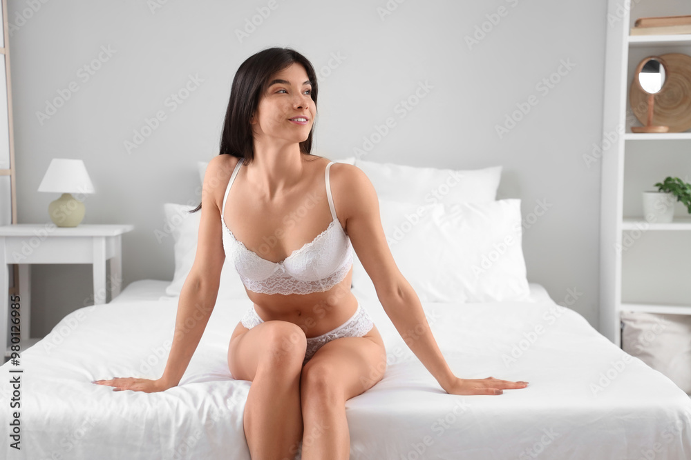 Young woman in white underwear sitting on bed at home Young woman in white underwear sitting on bed at home