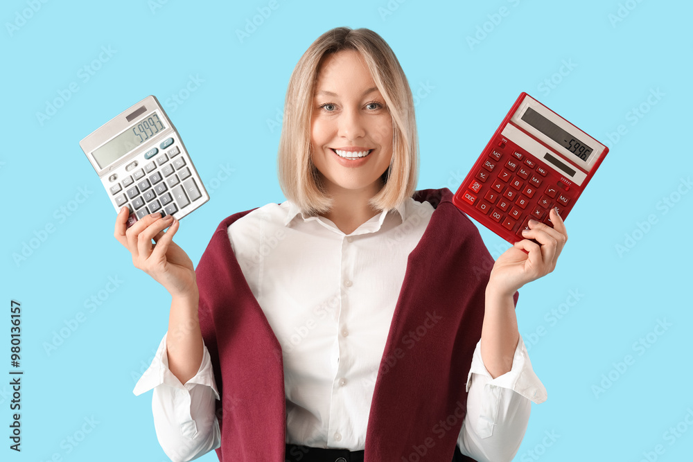 Mature female math teacher with different calculators on blue background Mature female math teacher with different calculators on blue background
