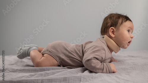 Portrait of a newborn baby lying on his stomach in an orthopedic collar.