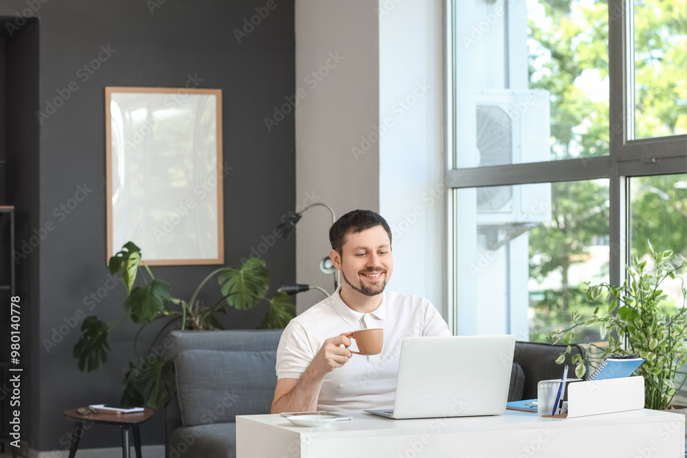 Young male teacher with laptop and cup of coffee giving online lesson at home Young male teacher with laptop and cup of coffee giving online lesson at home