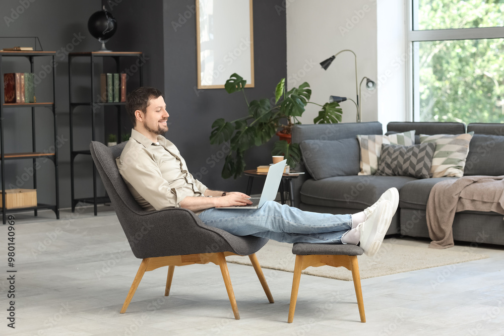 Young male teacher in armchair with laptop giving online lesson at home Young male teacher in armchair with laptop giving online lesson at home