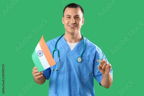 Male doctor with flag of India and syringe on green background. National Doctor's Day celebration photo