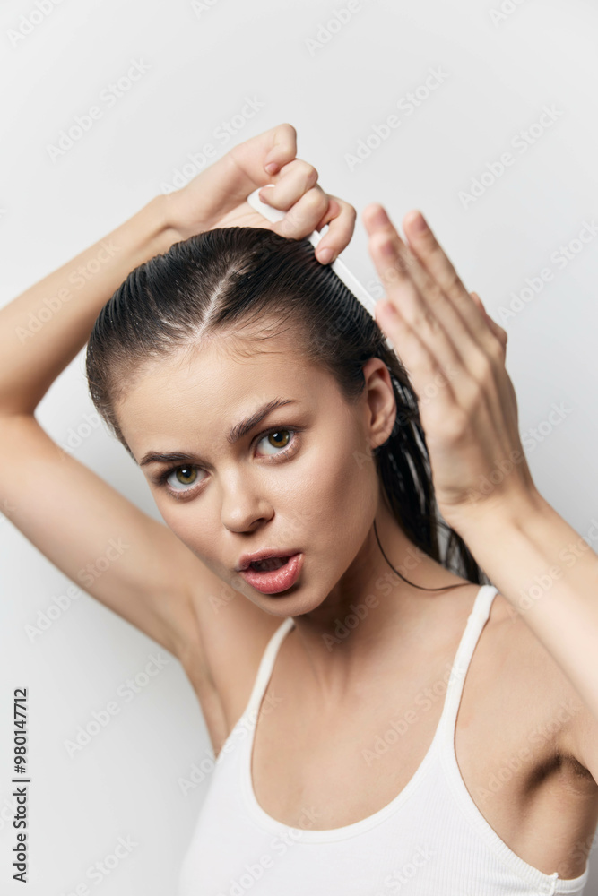 Woman styling wet hair, focusing on personal grooming and beauty routines, showcasing concentration and determination in a minimalistic setting Woman styling wet hair, focusing on personal grooming and beauty routines, showcasing concentration and determination in a minimalistic setting