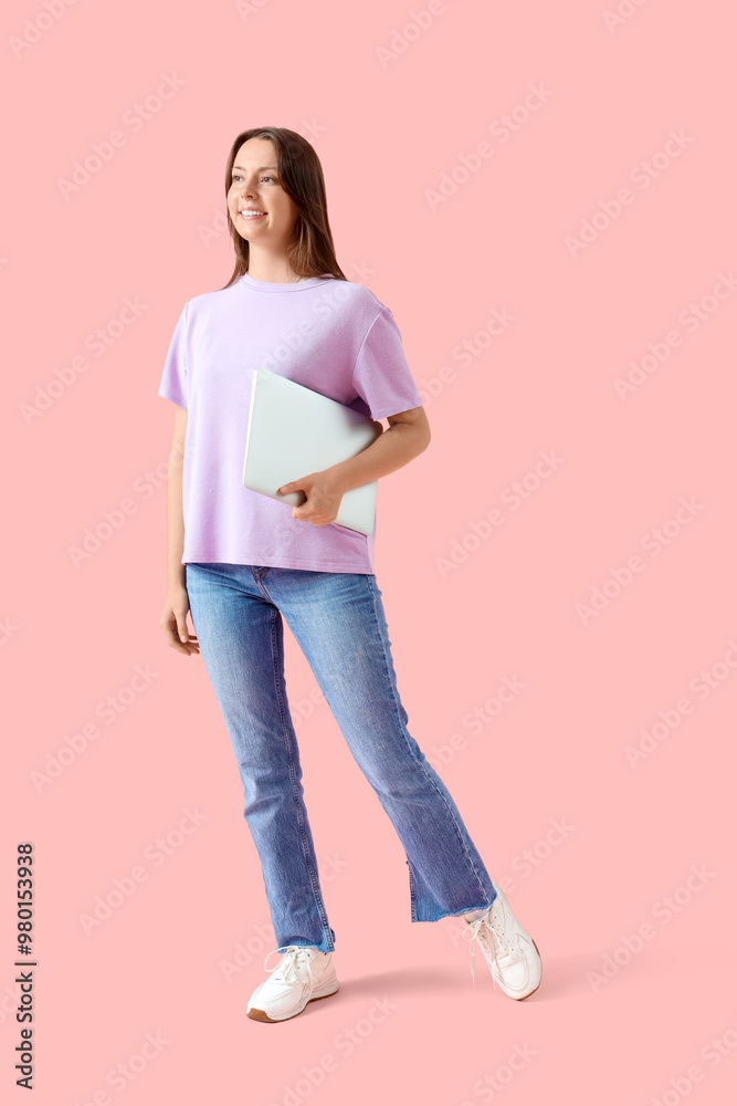Young woman with laptop walking on pink background Young woman with laptop walking on pink background