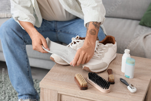 Young man cleaning sneakers...