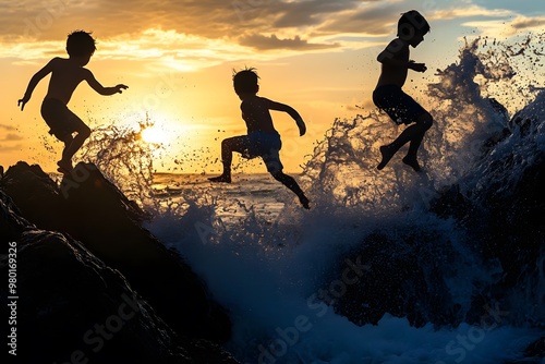 Several children climbing over large, jagged rocks by the ocean’s edge. Their silhouettes appear adventurous as the waves crash behind them