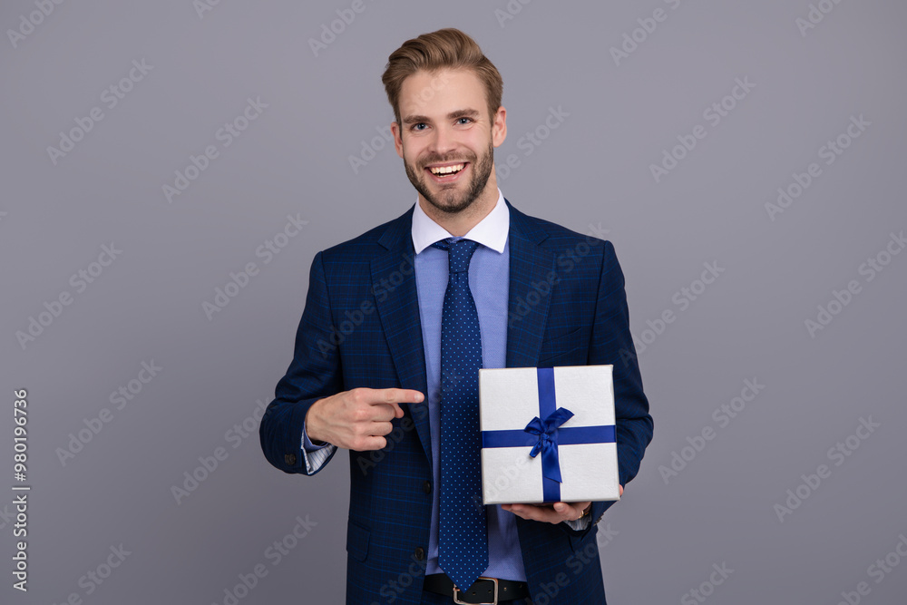 Successful boss share gift box. Businessman prepare for romance date. Business reward. Business man with corporate gift box isolated on grey. Corporate present. Mens day. Pointing finger Successful boss share gift box. Businessman prepare for romance date. Business reward. Business man with corporate gift box isolated on grey. Corporate present. Mens day. Pointing finger