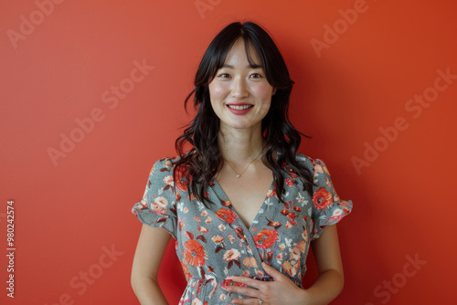 A young woman smiles at the camera with a red background