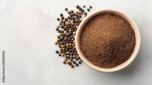 A bowl of brown spice with whole pepper grains scattered around, perfect for culinary use or spice shop imagery.