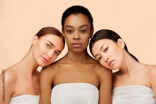 Three Sensual Multicultural Girls Wrapped In Bath Towels Posing Over White Background. Studio Shot photo