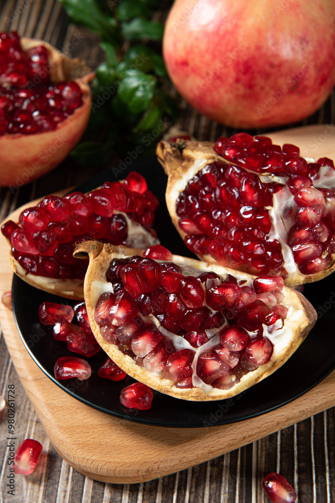 open pomegranates, and pomegranate seeds on wooden table. open pomegranates, and pomegranate seeds on wooden table.