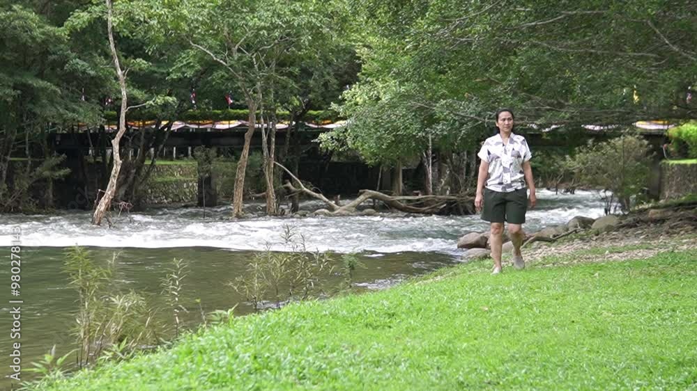 Asian woman walking along the river in the forest Asian woman walking along the river in the forest