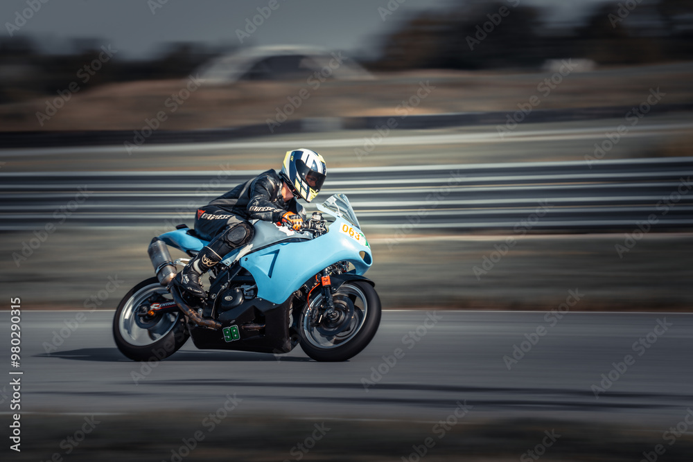 A man rides a blue motorcycle along a winding road against a blurred backdrop A man rides a blue motorcycle along a winding road against a blurred backdrop