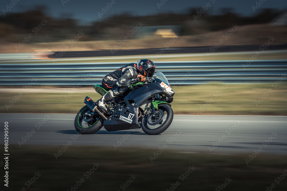 A man rides on a motorcycle's back seat, navigating a winding, lush-green field-lined road A man rides on a motorcycle's back seat, navigating a winding, lush-green field-lined road