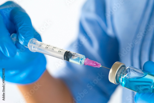 doctor's hand holds a syringe and a blue vaccine bottle at the hospital. Health and medical concepts