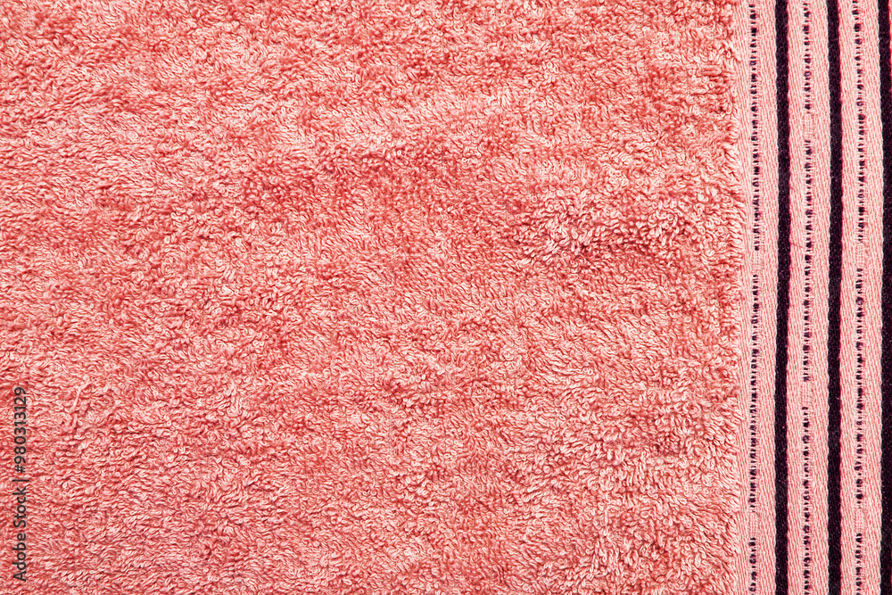 Fototapeta premium Close-up texture of a pink towel with a detailed look at the soft fabric and the subtle stripes along the edge