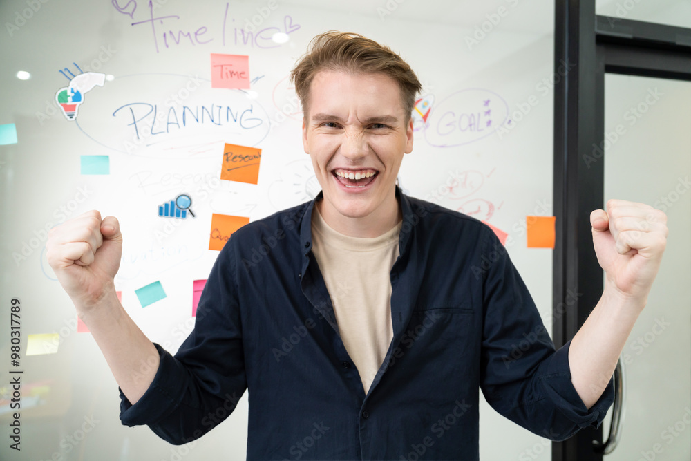Portrait of happy young businessman wearing blue casual uniform while standing in front of glass board with colorful sticky notes and mind map with confident at creative business meeting. Immaculate.