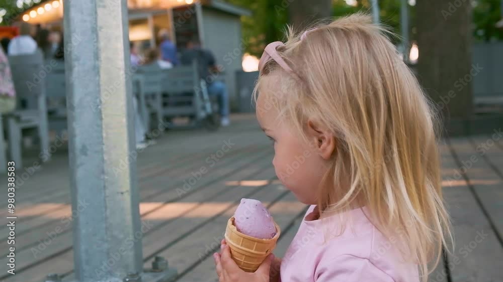 Little kid Caucasian toddler girl eating ice cream in the park.