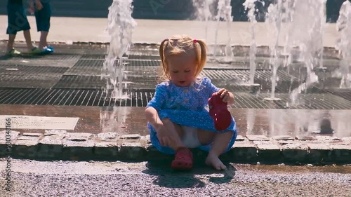 Cute Caucasian girl child walks in the park with fountains in the summer. Saint Petersburg, Russia - 26 July 2024