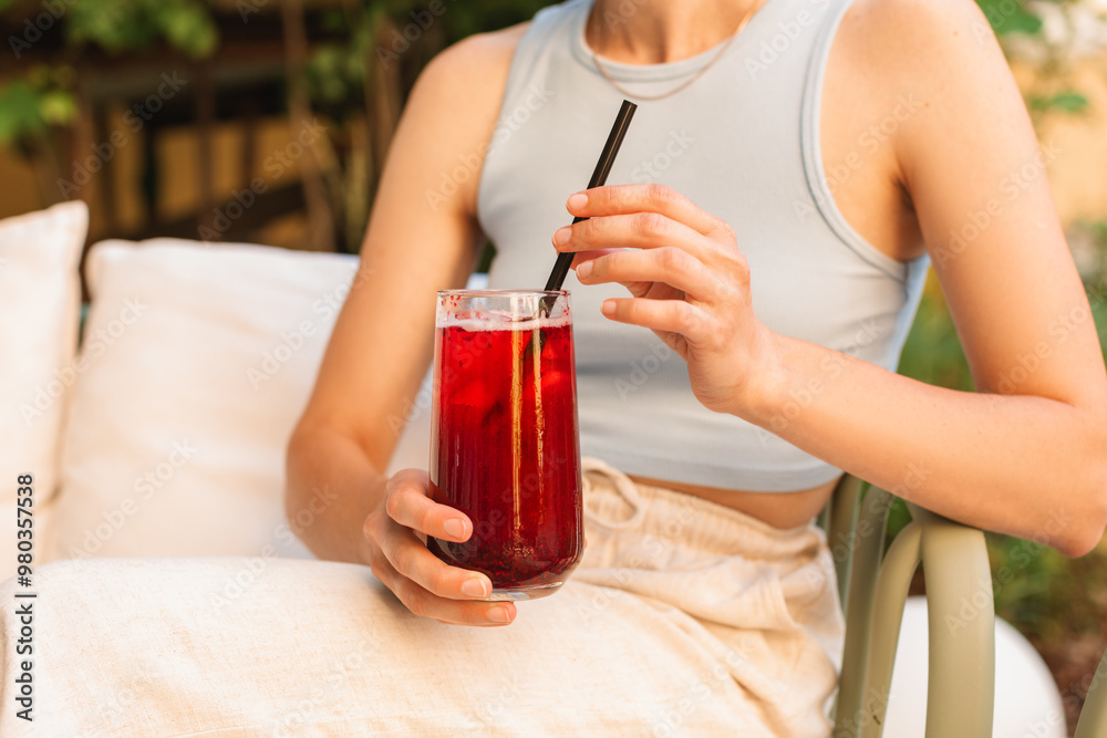 Close-up of a young woman drinking berry lemonade on the terrace of a cafe on a sunny morning. Close-up of a young woman drinking berry lemonade on the terrace of a cafe on a sunny morning.
