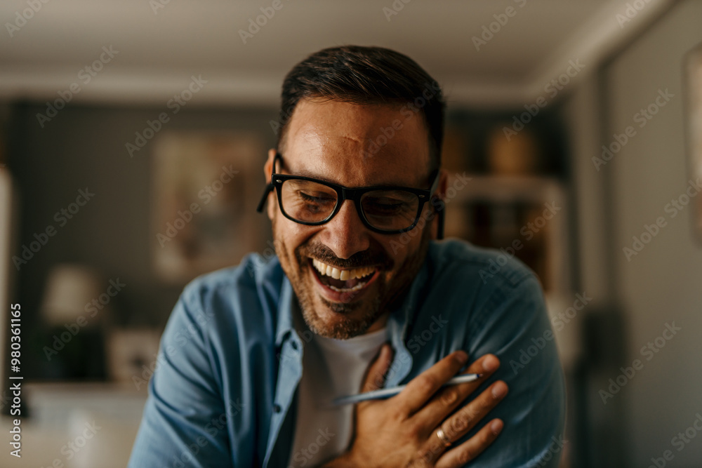 Handsome mid aged man sitting in the living room and having a video call over a smartphone Handsome mid aged man sitting in the living room and having a video call over a smartphone