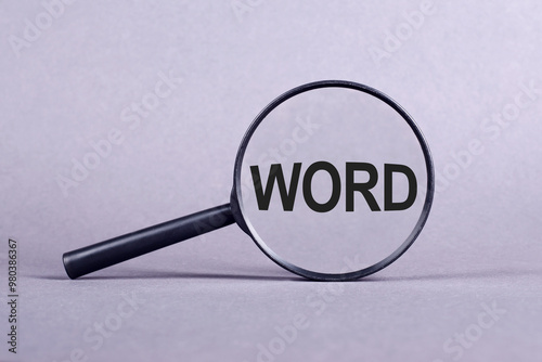 Magnifying Glass Focusing on the Text WORD Against a Plain Background photo