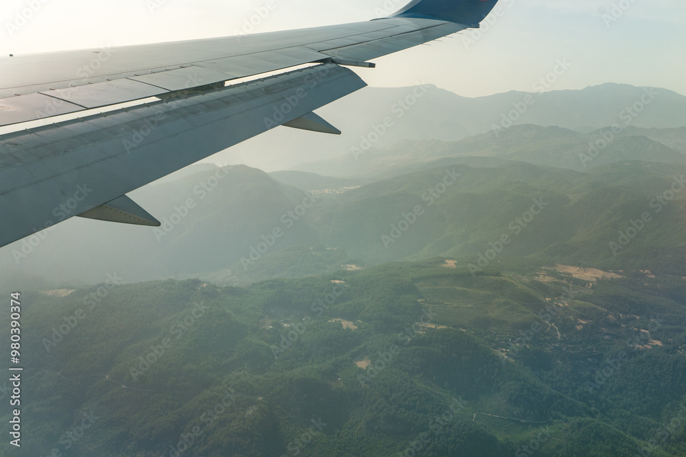 Airplane wing is visible from the window of a jet airliner. The concept of passenger air travel and air tourism. Airplane wing is visible from the window of a jet airliner. The concept of passenger air travel and air tourism.
