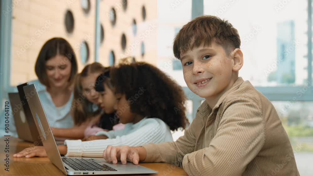 Boy looking at camera with multicultural friend learning prompt at STEM technology class. Multicultural student study about engineering code and programing system with blurring background. Erudition. Boy looking at camera with multicultural friend learning prompt at STEM technology class. Multicultural student study about engineering code and programing system with blurring background. Erudition.