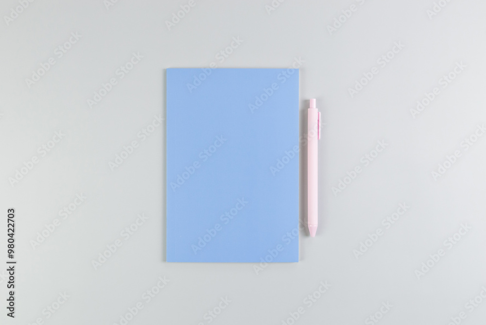 Top view of blue notebook, pink pen on grey background. School, office wallpaper. Flat lay, copy space. Top view of blue notebook, pink pen on grey background. School, office wallpaper. Flat lay, copy space.