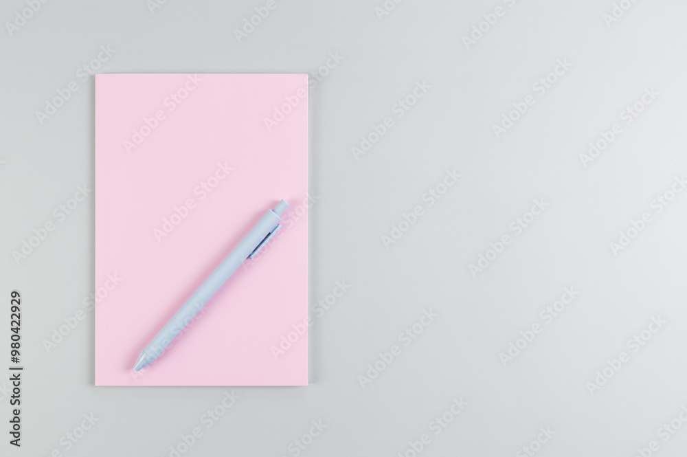 Top view of pink notebook, blue pen on grey background. School, office wallpaper. Flat lay, copy space. Top view of pink notebook, blue pen on grey background. School, office wallpaper. Flat lay, copy space.