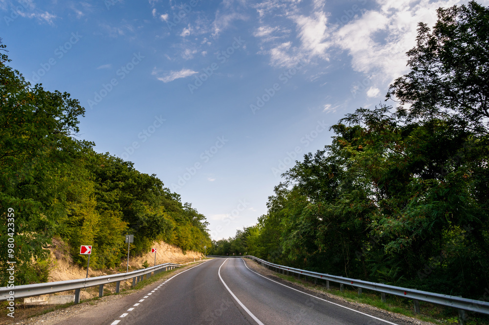Road turn. Landscape highway, forest, mountains and sky on the horizon. Empty long mountain road to the horizon on a sunny summer day with dramatic cloudy sky. Highway turn panoramic view. Road turn. Landscape highway, forest, mountains and sky on the horizon. Empty long mountain road to the horizon on a sunny summer day with dramatic cloudy sky. Highway turn panoramic view.