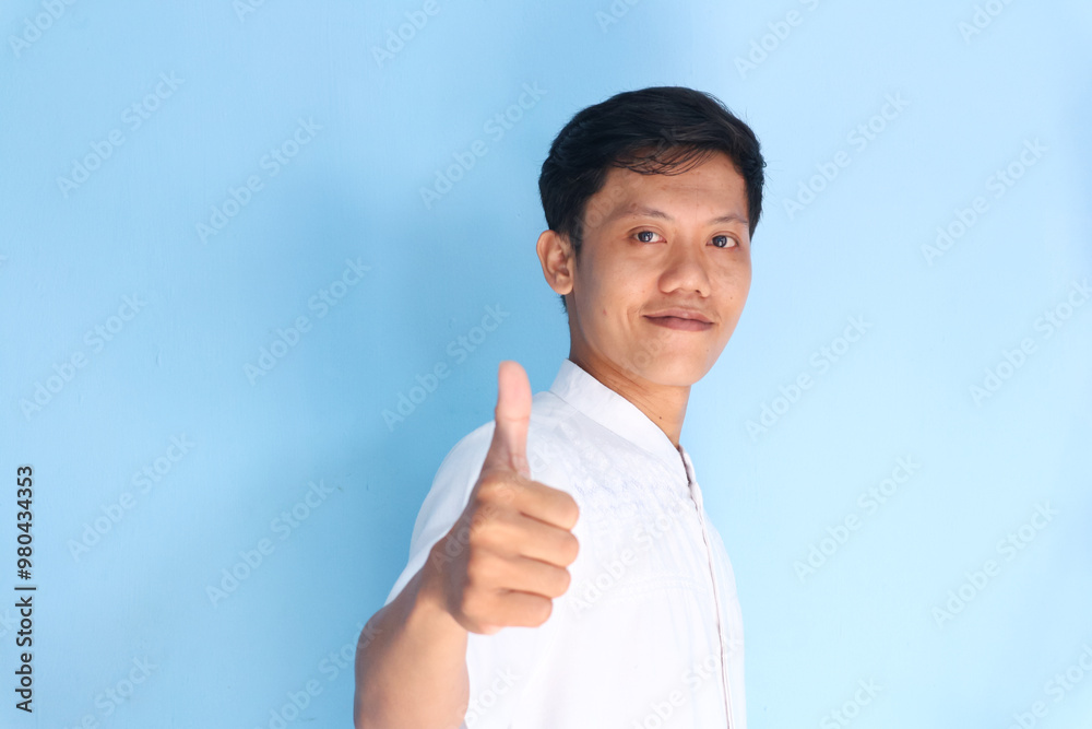 Asian man wearing a white shirt, posing with a thumbs-up gesture, as if expressing approval Asian man wearing a white shirt, posing with a thumbs-up gesture, as if expressing approval